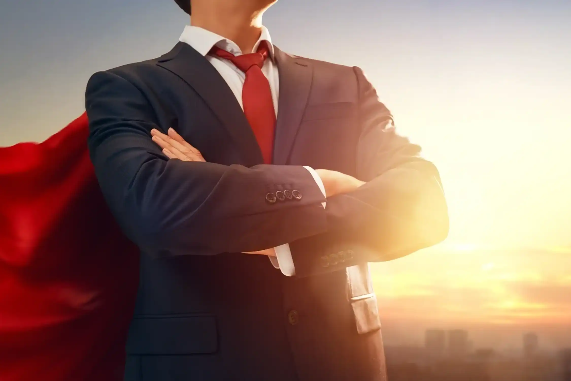 Businessman with red cape at sunrise.