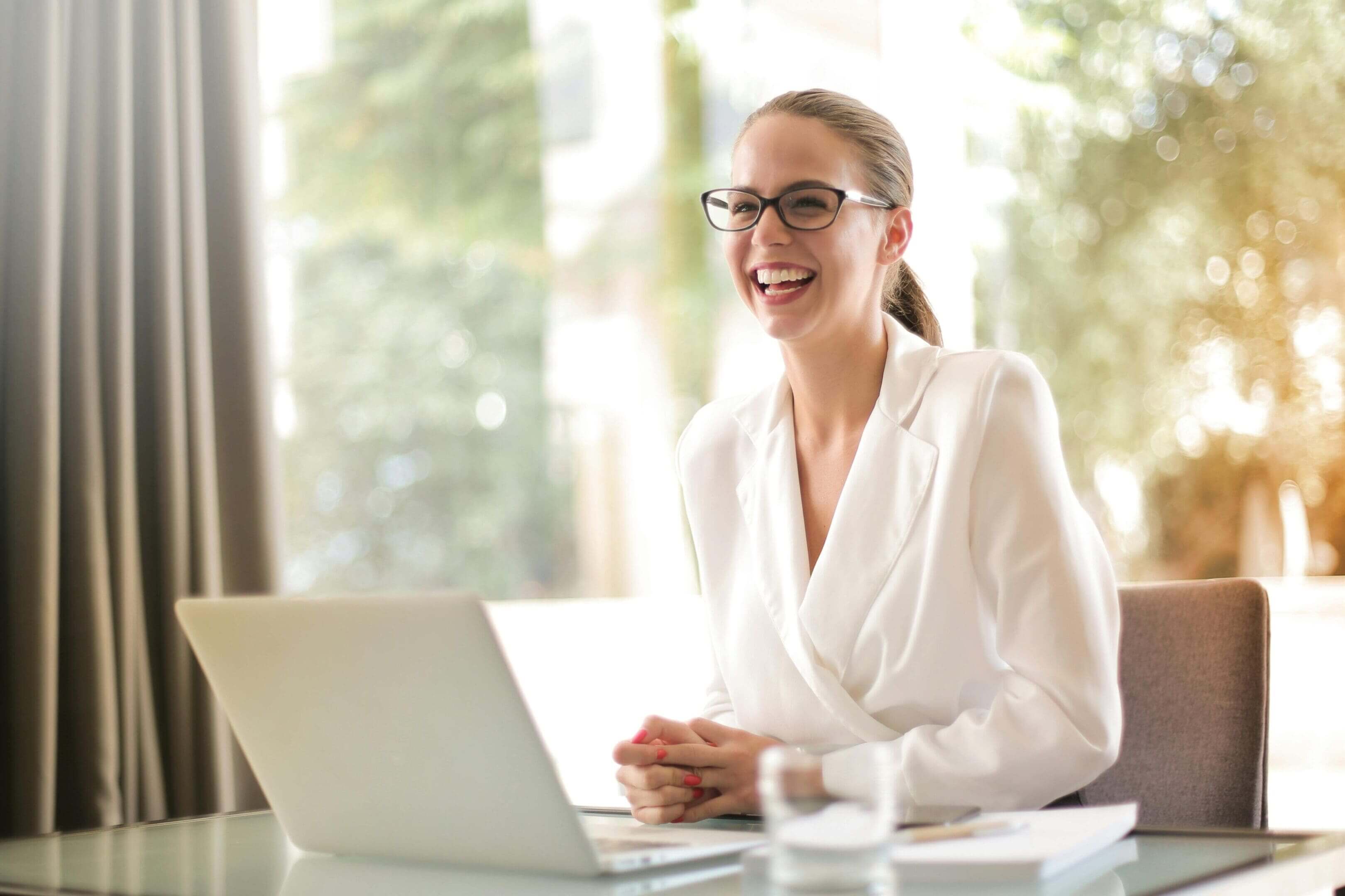 A woman sitting at a table with her laptop.