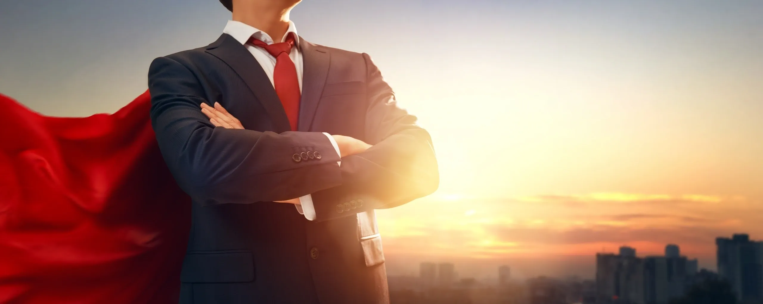 Businessman with red cape at sunrise.