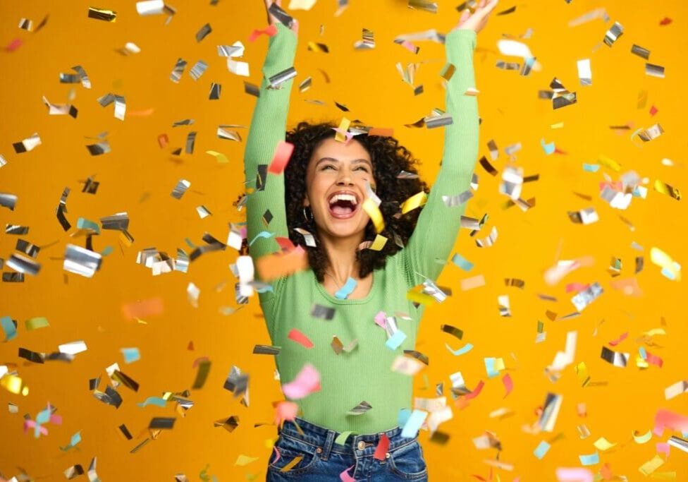 Woman celebrating with colorful confetti falling.